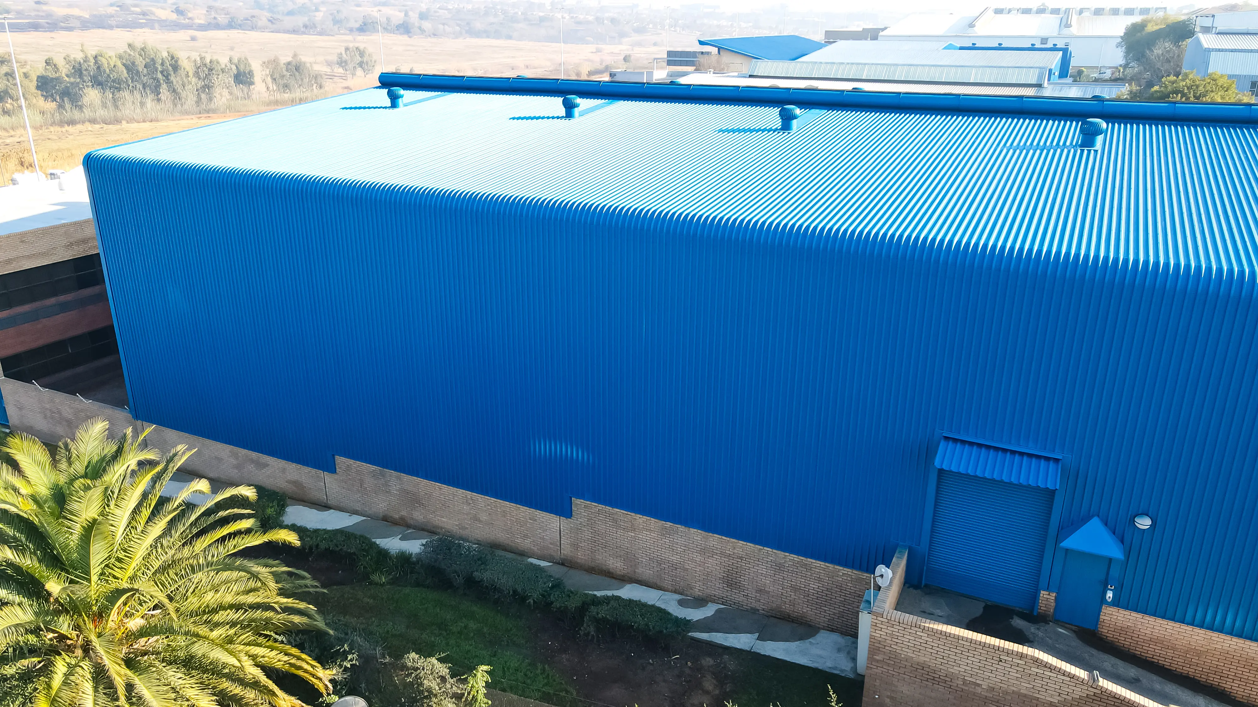 Aerial view of a completed industrial roof restoration with new blue IBR roof sheeting and cladding by Sicon Group