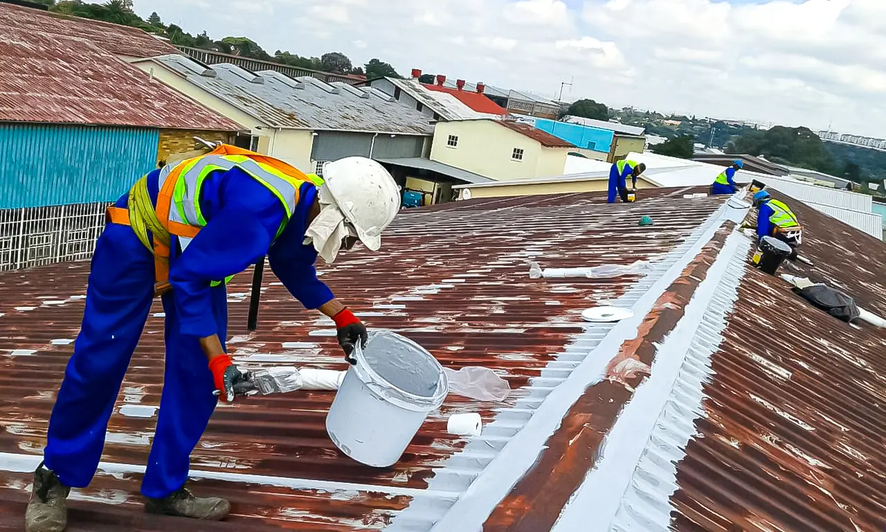 Sicon Group crew in safety harnesses treating a corroded industrial roof and sealing the seams with waterproofing