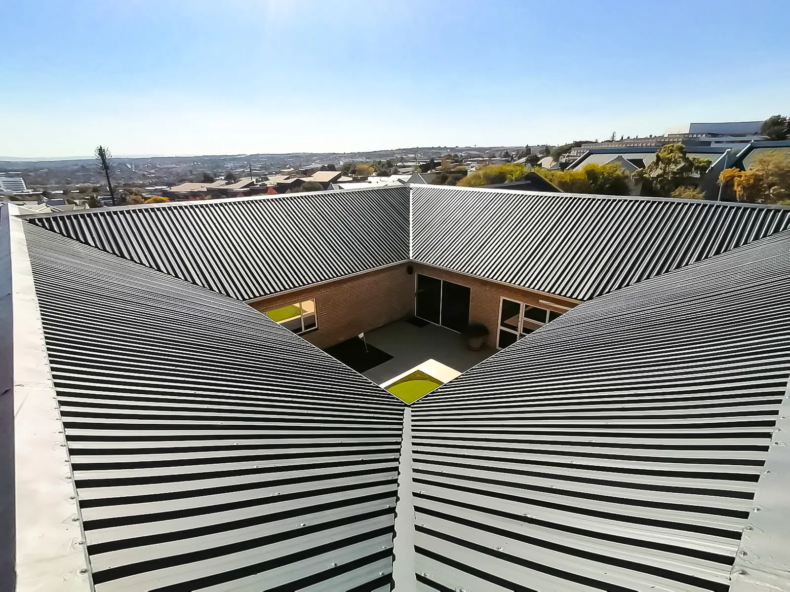 Aerial view of an industrial roof showing valley gutters channelling rainwater toward the courtyard, by Sicon Group