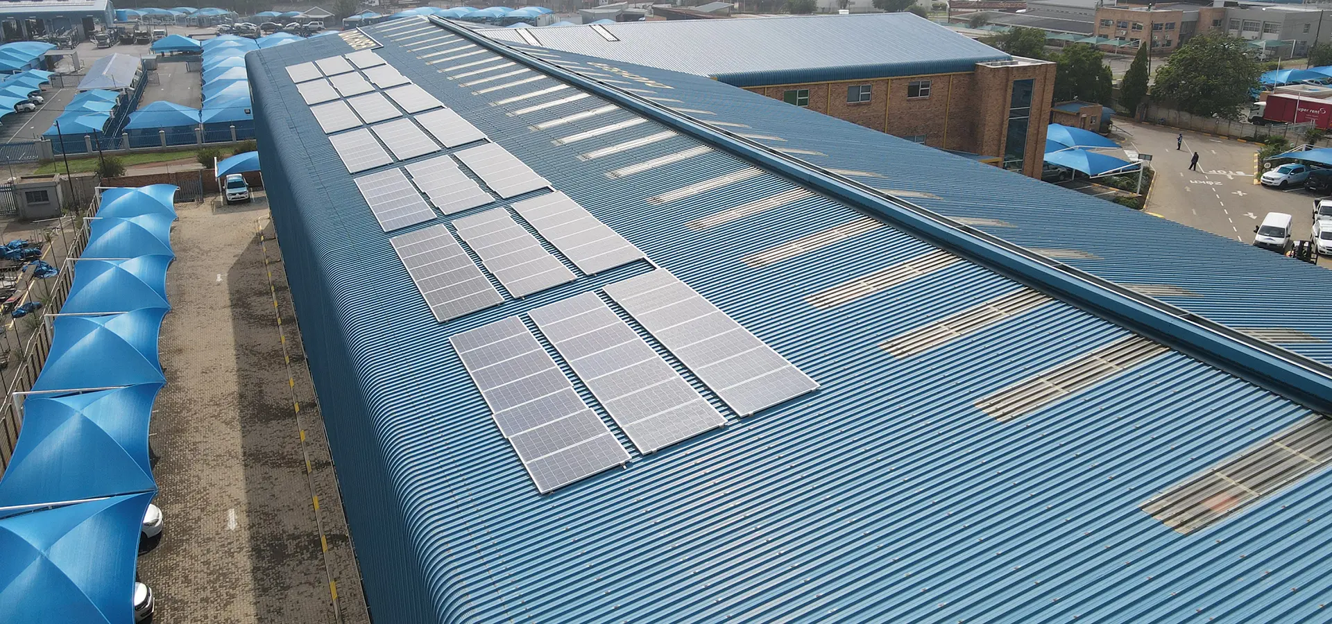 Solar array mounted on a newly coated industrial roof, with roof-light strips running alongside