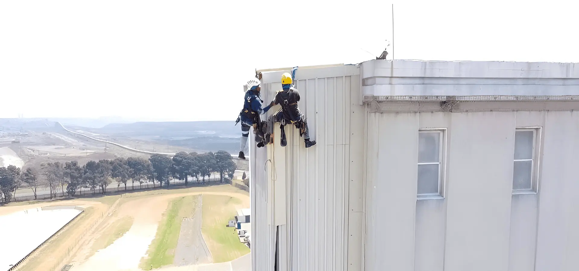 Two Sicon Group rope-access technicians abseiling down the side of a tall industrial building