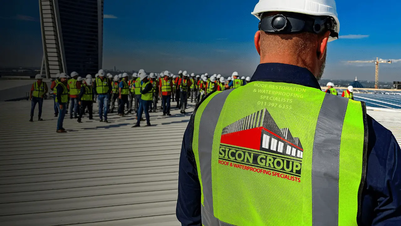 Sicon Group foreman in a branded hi-vis vest overseeing the roofing crew on a high-rise rooftop in Johannesburg