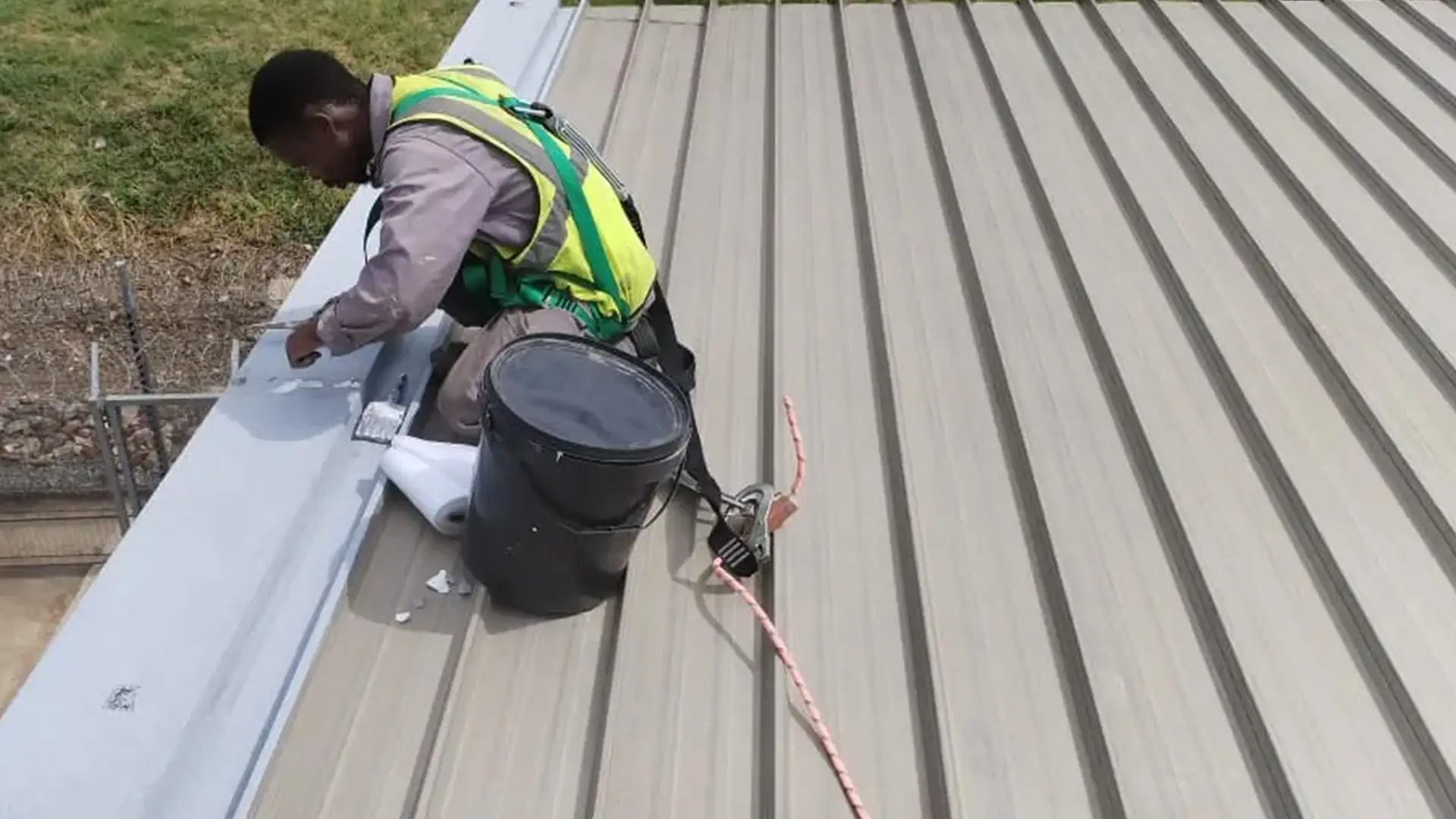 Sicon Group technician performing rust removal and upkeep on a corrugated industrial roof