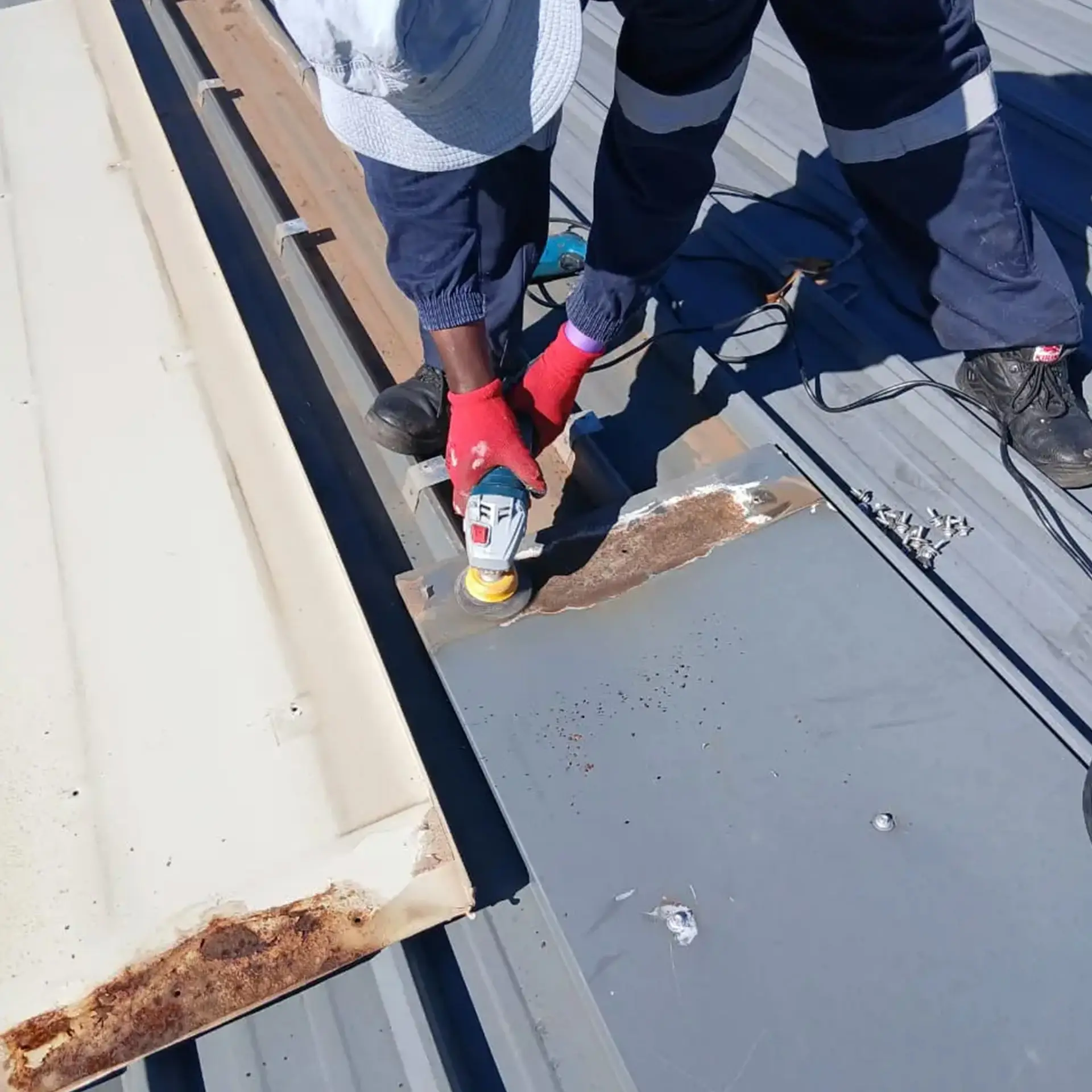 Sicon Group technician maintaining and coating a commercial roof edge near a solar array