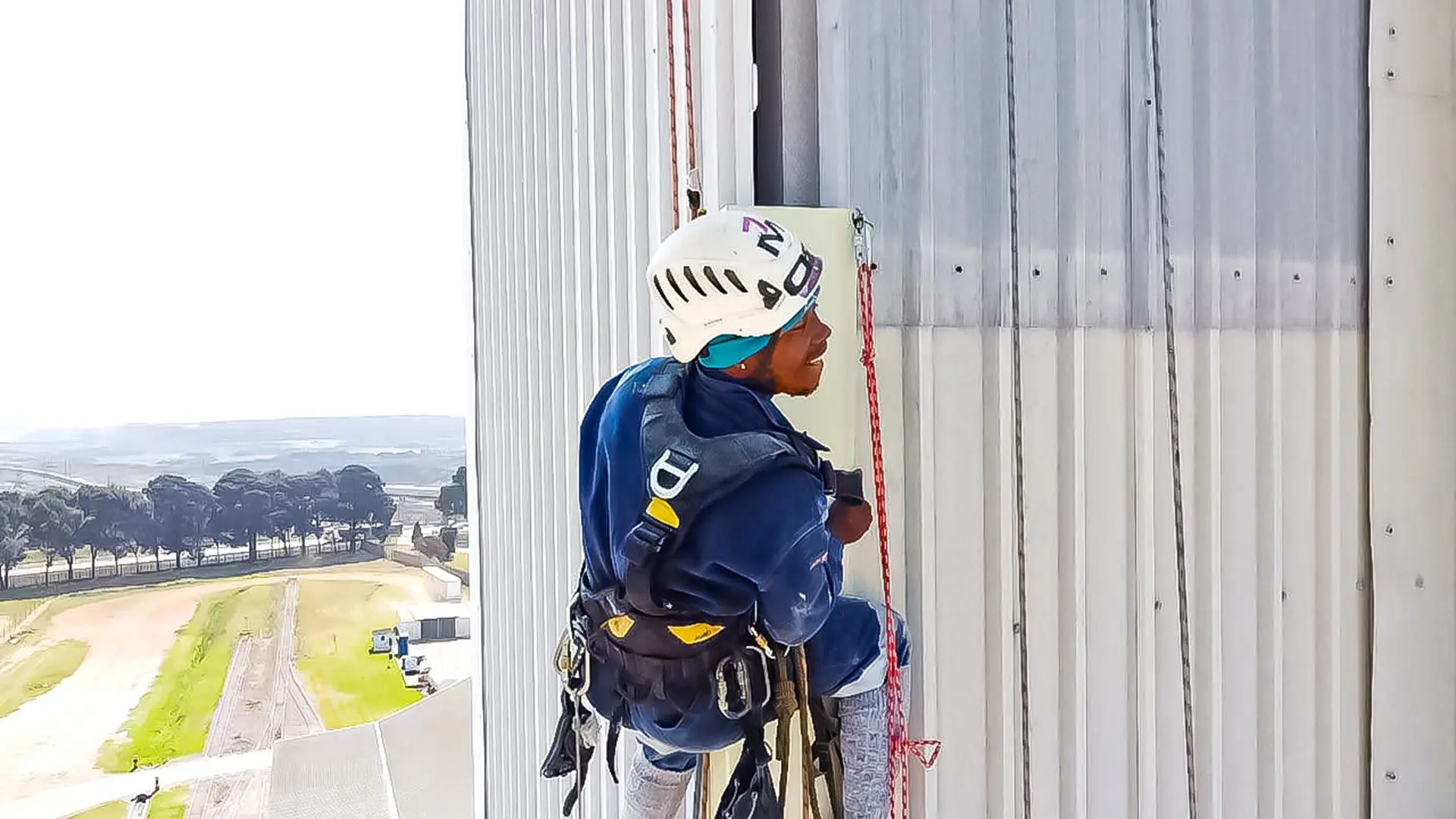 Technicians performing maintenance on a tall metal-clad building using rope access, Johannesburg